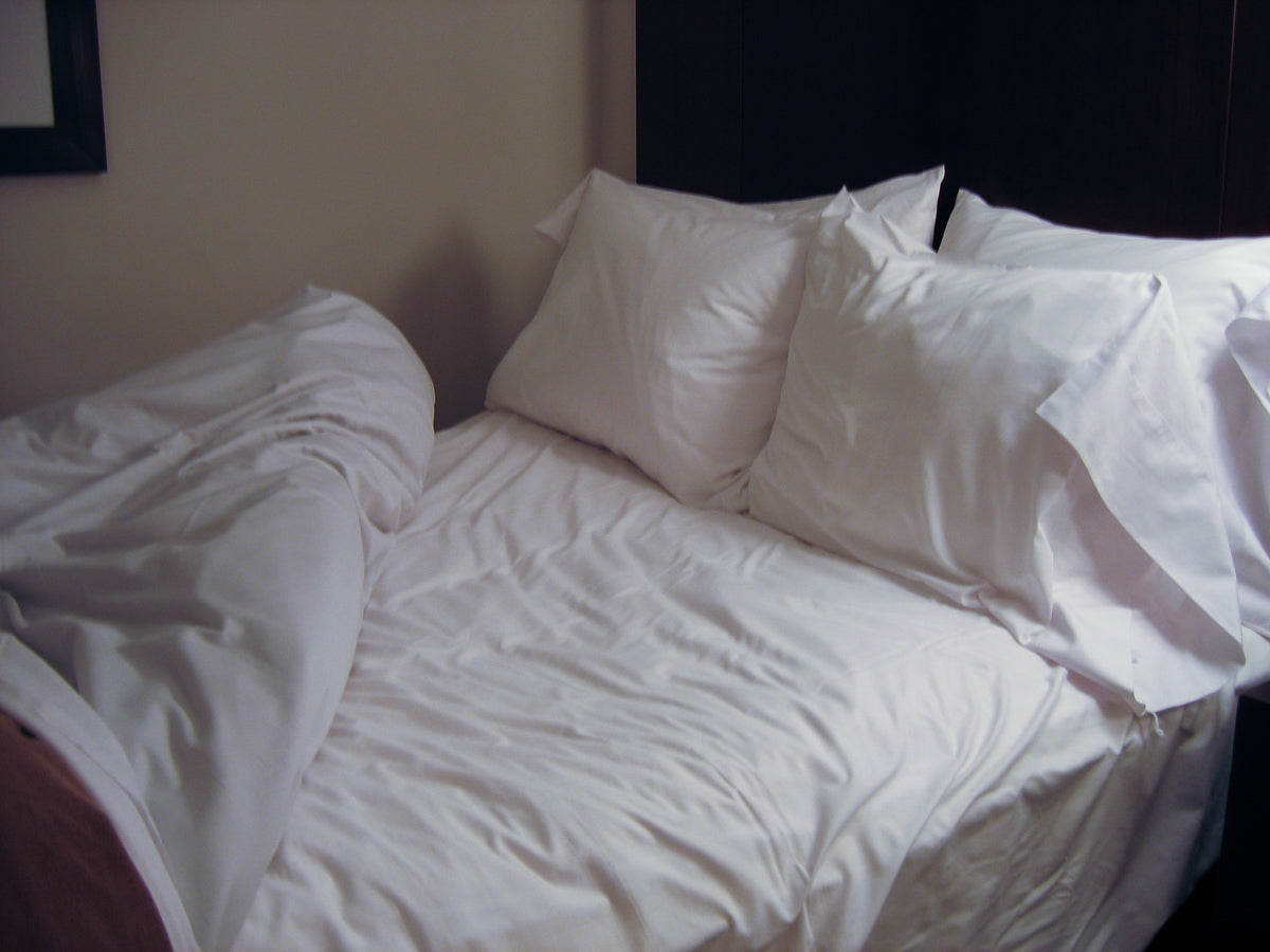 Opgemaakt bed met wit beddengoed in een rustige hotelkamer