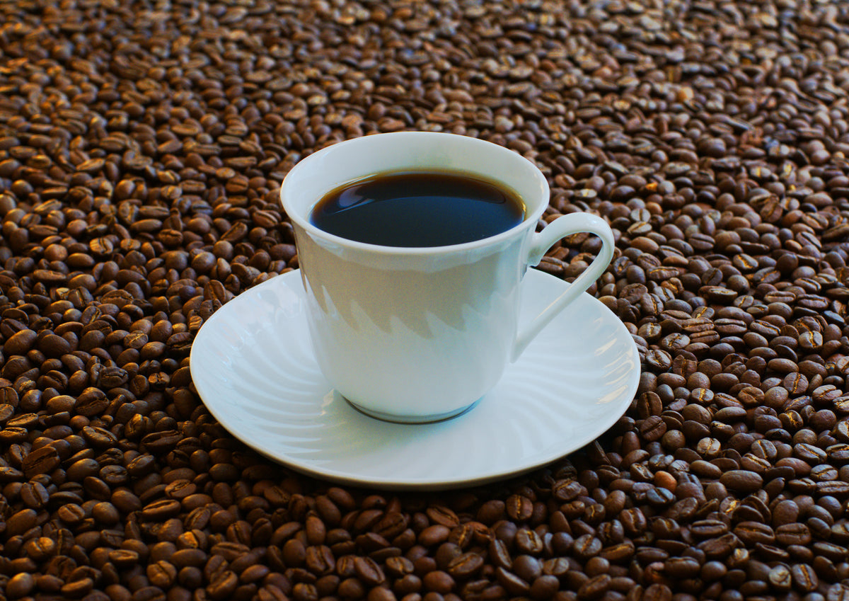 Kopje koffie omringd door koffiebonen